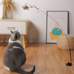 Cat chasing the dangling feather lure of the Aevvon interactive cat wand toy in a living room